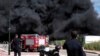 Israeli policemen stand next to smoke from a fire following incoming rockets from Lebanon to Israel in Bezet, northern Israel, April 6, 2023.