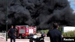 Israeli policemen stand next to smoke from a fire following incoming rockets from Lebanon to Israel in Bezet, northern Israel, April 6, 2023.