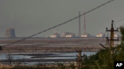 Pembangkit listrik tenaga nuklir Zaporizhzhia, yang terbesar di Eropa, terlihat di latar belakang Waduk Kakhovka yang dangkal setelah bendungan runtuh, di Energodar, Ukraina yang diduduki Rusia, 27 Juni 2023. (Foto: AP)