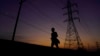 A jogger passes power lines during a sunset run, Aug. 20, 2023, in San Antonio. Triple-digit temperatures continue to stress the state's power grid.