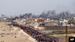 Sejumlah warga Palestina tampak berbaris menanti truk bantuan untuk lewat ke wilayah mereka di bagian tengah Jalur Gaza, pada 19 Mei 2024. (Foto: AP/Abdel Kareem Hana)
