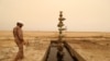 Seorang pekerja tampak berjalan melewati sumur minyak di ladang minyak Sindbad di dekat perbatasan antara Iran dan Irak di Basra, Irak, pada 23 April 2018. (Foto: Reuters/Essam Al-Sudani)
