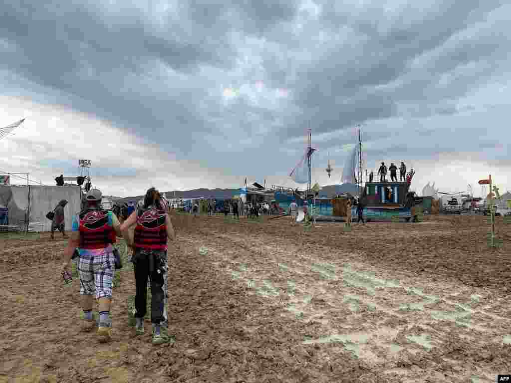 Attendees walk through a muddy desert plain, Sept. 2, 2023, after heavy rains in Nevada's Black Rock desert. All events at the counterculture festival, which drew some 70,000 people, were canceled after rain tore down structures for dance parties, art installations and other eclectic entertainment. 