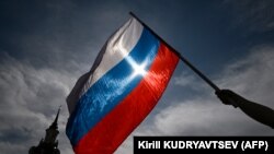 Seorang pria mengibarkan bendera nasional Rusia di pusat kota Moskow pada 11 Juni 2023. (Foto: AFP/Kirill KUDRYAVTSEV)