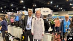 Para pemegang saham Berkshire Hathaway berfoto dengan poster investor dan CEO Warren Buffett dalam rapat pemegang saham tahunan Bershire Hathaway di Omaha, Nebraska, Jumat, 3 Mei 2024. (Foto: Josh Funk/AP Photo)

