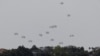 Humanitarian aid falls through the sky towards the Gaza Strip after being dropped from an aircraft, amid the ongoing conflict between Israel and the Palestinian Islamist group Hamas, as seen from Israel, April 25, 2024. 