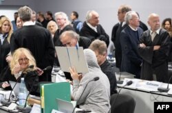 Seorang terdakwa menyembunyikan wajahnya di balik map di ruang sidang, saat terdakwa Pangeran Heinrich XIII Reuss (atas, 2ndR) berdiri di samping pengacaranya di ruang sidang di Frankfurt am Main, 21 Mei 2024.