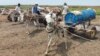 Men queue to fill tanks with water from a well in Gadaref, Sudan, on Aug. 17, 2023. For more than three months, millions have been rationing water and electricity, unable to reach the few health care facilities that still function in the country.
