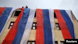 FILE - Activists unfurl Bosnian Serb flags on a building on the Serb Republic's national holiday, banned by Bosnia and Herzegovina's constitutional court, in East Sarajevo, Jan. 9, 2023.
