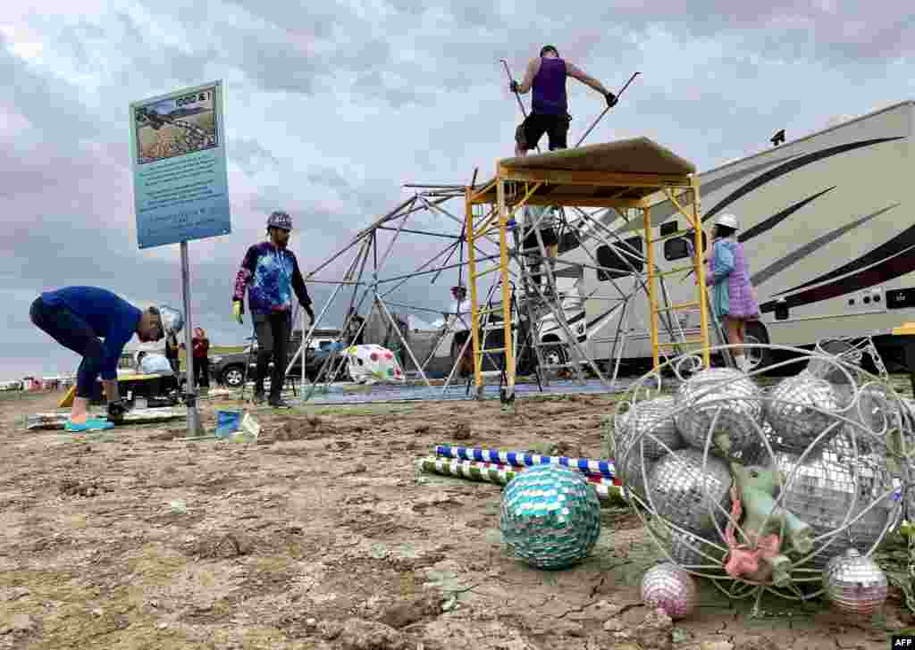 Attendees known as "burners" strike down their Unicorner camp before new rainfalls in a muddy desert plain, Sept. 3, 2023, after heavy rains turned the annual Burning Man festival site in Nevada's Black Rock desert into a mud pit.