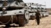 An Israeli soldier walks near tanks parked near the southern Israel-Gaza border, amid the ongoing conflict between Israel and the Palestinian Islamist group Hamas, in Israel, April 28, 2024.