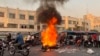 A picture obtained by AFP outside Iran, shows people gathering next to a burning motorcycle in the capital Tehran on October 8, 2022.