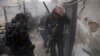 A Syrian rebel grabs his head as the smoke subsides, after the wall the group was taking shelter behind was hit by a shell fired from a government controlled army checkpoint, during fighting between the two sides in the Ain Tarma neighborhood of Damascus 