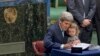 U.S. Secretary of State John Kerry holds his granddaughter as he signs the Paris agreement on climate change at U.N. headquarters, April 22, 2016. 