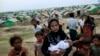 FILE - An internally displaced Rohingya woman holds her newborn baby surrounded by children in the foreground of makeshift tents at a camp for Rohingya people in Sittwe, northwestern Rakhine State, Burma.