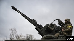 A Ukrainian soldier keeps position sitting on a ZU-23-2 anti-aircraft gun at a frontline, northeast of Kyiv, March 3, 2022. 