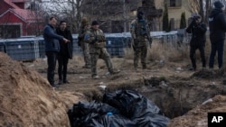 На фото: Люди стоять біля братської могили в Бучі, на околиці Києва, Україна, понеділок, 4 квітня 2022 року. (AP Photo/Rodrigo Abd)