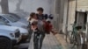 An injured boy carries an injured girl as he runs towards a safe area a few minutes after the suicide bombing in Quetta, Pakistan, Feb. 6, 2016. 