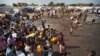 FILE - A year after fighting broke out in South Sudan, people gathered around a water truck to fill containers at a U.N. compound in Juba that had become home to thousands of displaced people, Dec. 29, 2013.