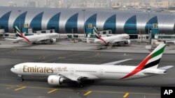 An Emirates plane taxis to a gate at Dubai International Airport at Dubai International Airport in Dubai, United Arab Emirates. Emirates Airline, the world's biggest international air carrier by traffic, said Wednesday it is cutting flights to five U.S. cities because of a drop in demand since President Donald Trump sought to curb immigration from several Muslim-majority countries and imposed restrictions on passengers carrying electronic devices on flights to the United States, April 19, 2017. 