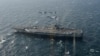 FILE - In a photo provided by Japan's Air Self-Defense Force, two U.S. F/A-18s and Japanese F-15s fly over the USS Ronald Reagan toward a joint military exercise at an undisclosed location, Nov. 10, 2017.