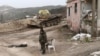 Syrian troops stand, with a destroyed tank in the background, on a street in Salma, Syria, Jan. 22, 2016. Syrian government forces, relying on Russian air cover, have recently seized Salma, located in Syria's province of Latakia, from militants.