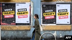 Seorang perempuan berjalan melewati poster yang menyerukan masyarakat untuk memberikan suara terkait referendum pencantuman hak-hak warga pribumi di dalam konstitusi, Melbourne pada 30 Agustus 2023. (Foto: AFP)