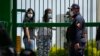 Margareth Baduel, en el centro, hija del difunto ministro de Defensa Raúl Isaías Baduel, habla con la Policía Nacional en la entrada del Cementerio Oriental en Caracas, Venezuela, el miércoles 13 de octubre de 2021.