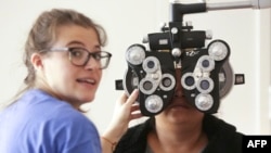 FILE - A woman gets an eye exam during a clinic at Key Arena, in Seattle, Washington, Oct. 28, 2016.