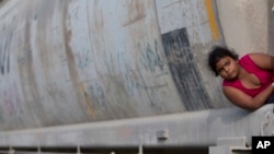 FILE - A young migrant girl waits for a freight train to depart on her way to the U.S. border, in Ixtepec, Mexico, July 12, 2014. In a report, the U.N. children's agency said that thousands of children trying to escape gang violence and poverty in Central