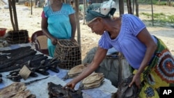 Une commerçante vend du poisson séché et de la viande fumée dans la commune de Maluku à Kinshasa, RDC, le 29 mai 2018. (AP Photo/John Bompengo)