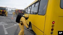 Український працівник у протирадіаційному костюмі перевіряє рівень радіації в автобусі під час тренувань у Запоріжжі, 29 червня 2023 р. AP Photo/Evgeniy Maloletka
