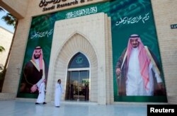 Para pria berjalan melewati mural yang menggambarkan Raja Arab Saudi Salman bin Abdulaziz Al Saud dan Putra Mahkota Mohammed bin Salman, di Riyadh, Arab Saudi, 9 November 2017. (Foto: Reuters)