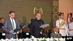 Presiden Pakistan Arif Alvi (Tengah) mengambil sumpah Anwaar-ul-Haq Kakar (kiri) sebagai Perdana Menteri sementara disaksikan Perdana Menteri Shehbaz Sharif (duduk kanan) di Gedung Presiden di Islamabad, 14 Agustus 2023. (AFP/DEPARTEMEN INFORMASI PERS PAKISTAN (PID)/XGTY)