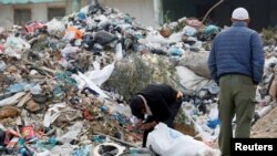 FILE - A man searches for usable items from a pile of garbage in Tunis, Tunisia, Nov. 23, 2019.