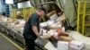 FILE - Steve Robino arranges packages on a conveyor belt at the main post office in Omaha, Neb., Dec. 14, 2017.