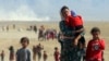 Displaced Yazidis, fleeing violence from forces loyal to the Islamic State group, head toward the Syrian border Aug. 11, 2014.