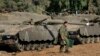 FILE - An Israeli soldier walks past tanks near the Israel and Gaza border, July 10, 2014. 