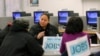 FILE - A case worker offers advice to job seekers at a San Francisco employment center.