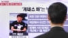 A passerby watches a local television broadcast in Seoul on May 2, 2013 showing a report and picture of Kenneth Bae (L), a Korean-American tour operator detained in North Korea. 