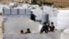 FILE - Displaced Syrian children climb a concrete wall at a refugee camp in the eastern Lebanese border town of Arsal, Lebanon, Aug. 5, 2019. 