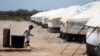 FILE - A Venezuelan migrant child walks next to a water tank, in a camp run by the U.N. refugee agency UNHCR, in Maicao, Colombia, May 6, 2019.