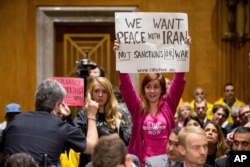 FILE - A Capitol Hill police officer asks members of the protest group CodePink to sit down during a Senate Foreign Relations Committee business meeting on Capitol Hill in Washington to debate and vote on the Iran Nuclear Agreement Review Act of 2015.