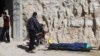 FILE - People stand near a dead body, after what rescue workers described as a gas attack in the town of Khan Sheikhoun in rebel-held Idlib, Syria, April 4, 2017.