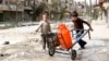 Children push a cart with water containers along a damaged street in old Aleppo, March 11, 2014. 