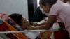 Naing Ngan Lynn, a candidate for National League for Democracy (NLD) party who was attacked on Thursday evening, lies on a hospital bed as his wife takes care of him in Yangon General hospital in Yangon, Myanmar, October 30, 2015.