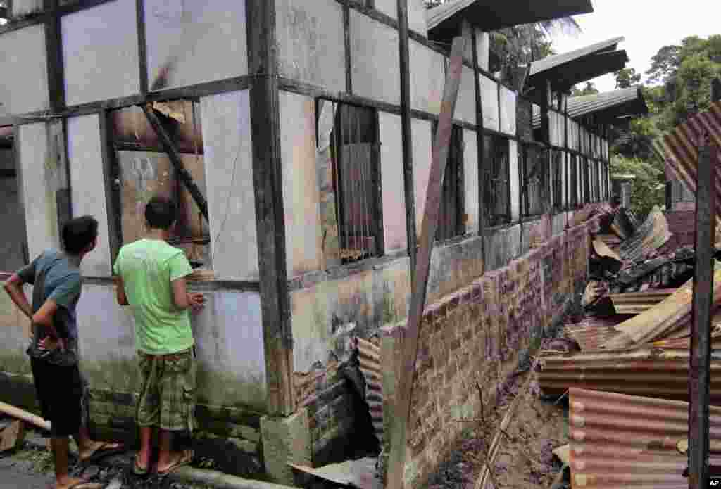 Indian people inspect a damaged house in Kokrajhar, India, July 23, 2012.