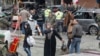 Women walk past as Lebanese army soldiers, gather at the site of Tuesday's explosion, in the Haret Hreik area in the southern suburbs of the Lebanese capital Beirut, Jan. 22, 2014.