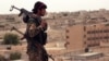 This photo provided by the Syria Democratic Forces (SDF) shows a fighter from the SDF carrying weapons as he looks toward the northern town of Tabqa, Syria, April 30, 2017.
