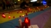 FILE - Man lights candles atop rainbow flag in solidarity with Pulse Orlando victims, Madrid, Spain, June 12, 2016.